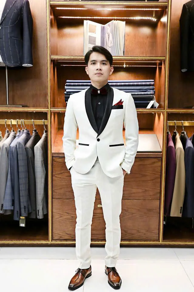 A white tuxedo with black lapels, a black shirt and a burgundy bow tie, a way to style a white jacket and black trousers with an accent