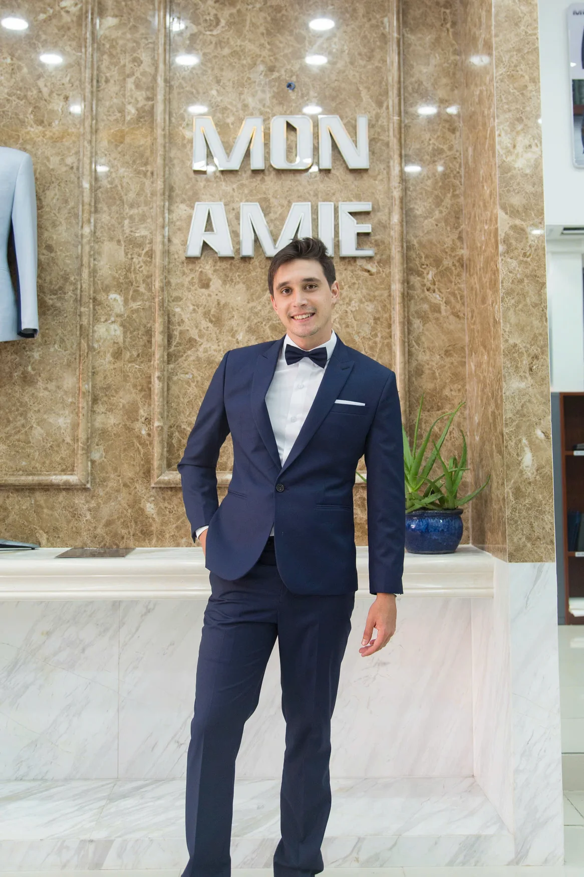 Chú rể mặc vest navy, nơ đen và khăn túi trắng, tay áo lộ sơ mi vừa đủ