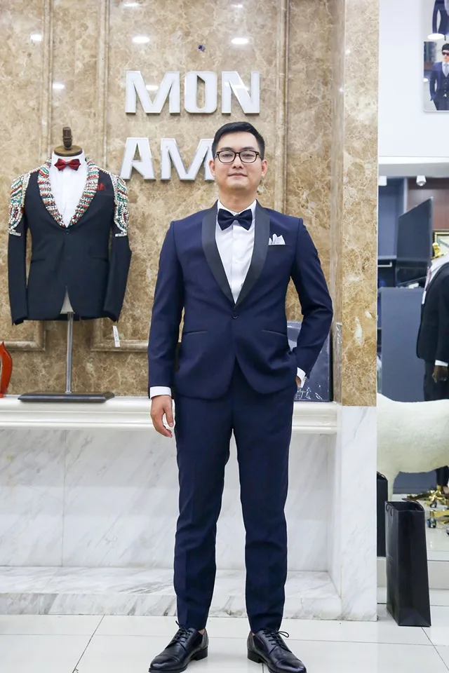 Tuxedo xanh navy ve lụa đen, nơ và khăn cài túi trắng, một lựa chọn may đo cho chú rể