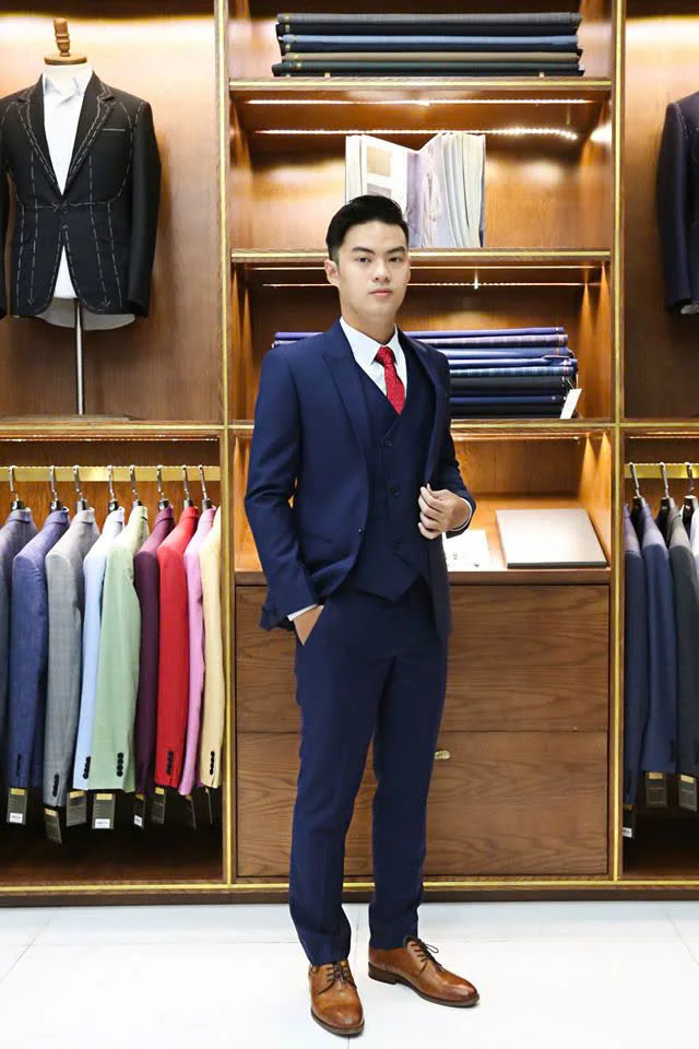 Gentleman in a navy three-piece suit, red tie and brown shoes