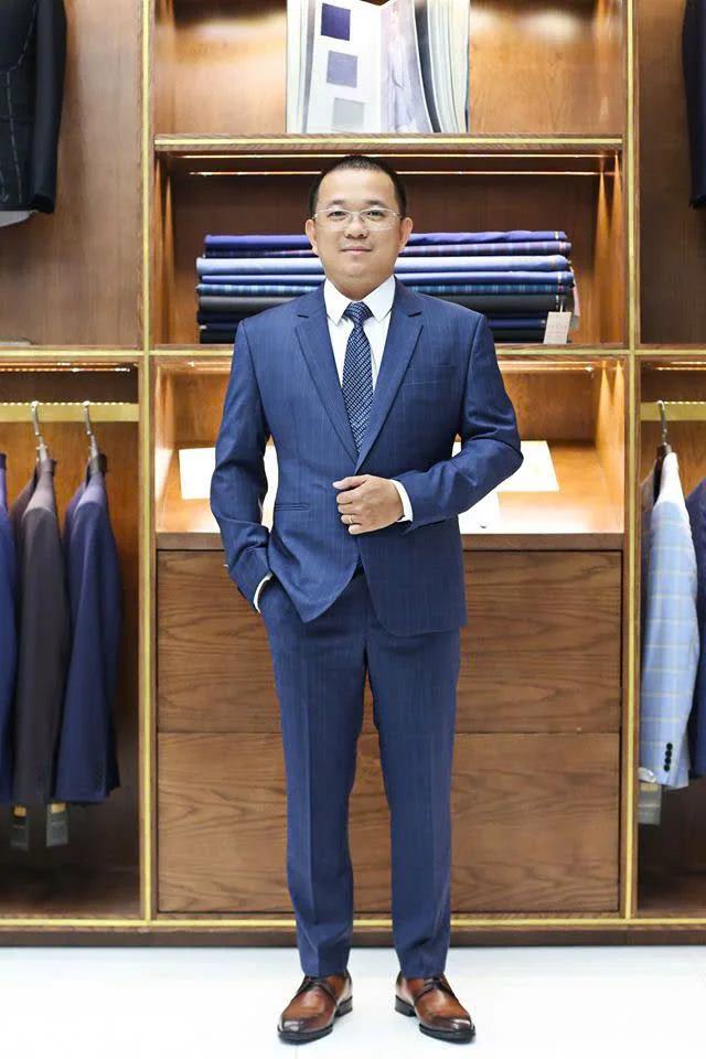 Man with glasses in a navy pinstripe suit, polka-dot tie