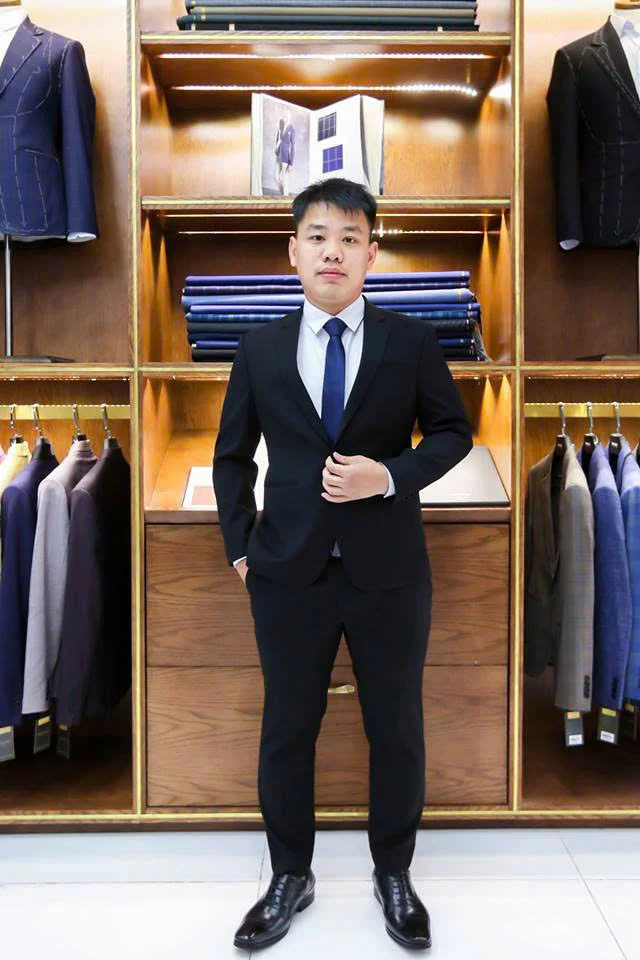 Chàng trai vest đen, cà vạt xanh navy, phối sơ mi sáng trong showroom gỗ