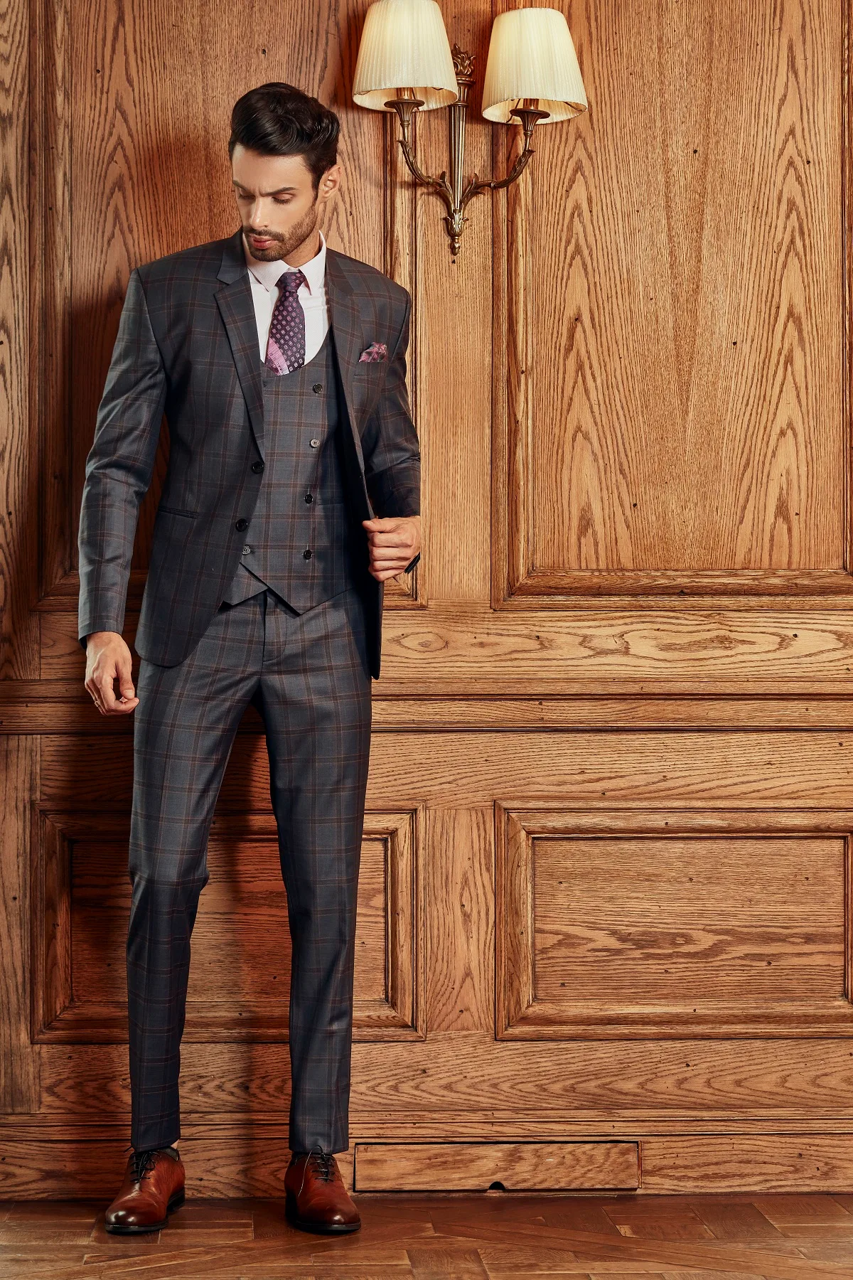 Suit ca-rô xám nâu ba mảnh, gile hai hàng khuy, cà vạt tím họa tiết, minh họa cách phối lớp cho người gầy