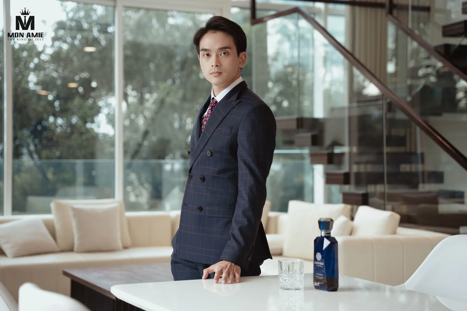 Navy double-breasted suit with a check of pale red stripes beside a white dining table