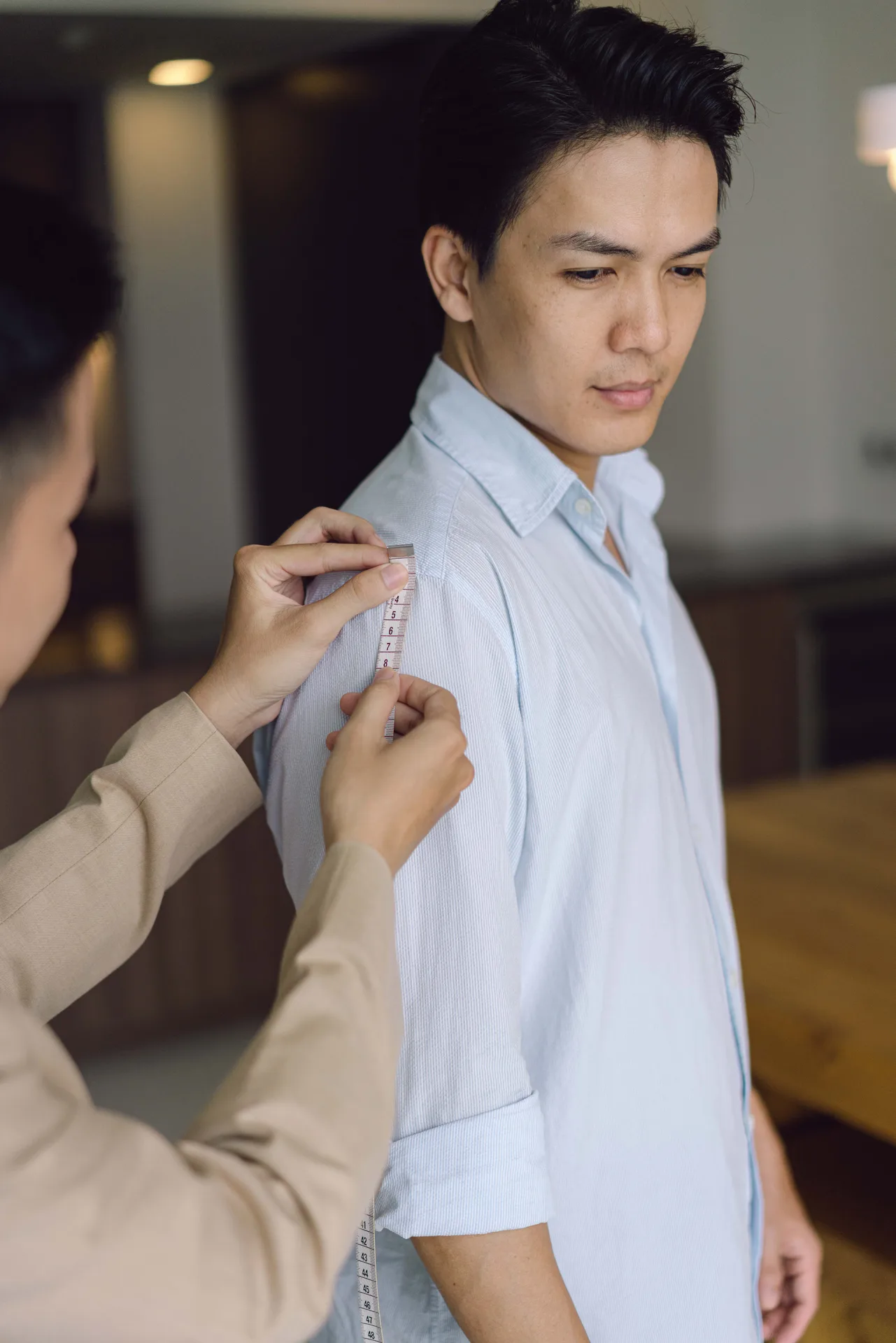 Close-up of a tape measure on the shoulder and sleeve, illustrating how to measure a suit jacket