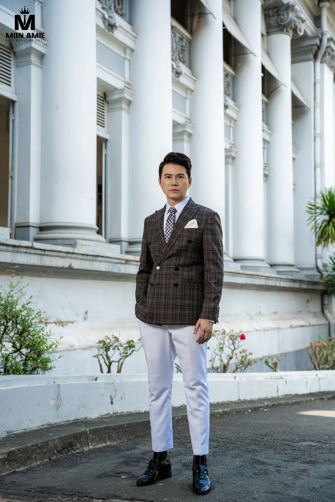 Suit caro nâu hai hàng khuy, quần trắng trước dãy cột