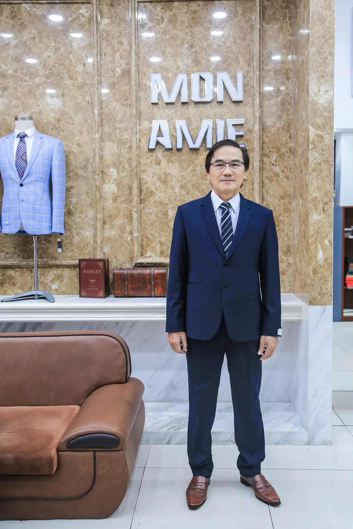 Quý ông vest navy đứng trước bảng hiệu Mon Amie