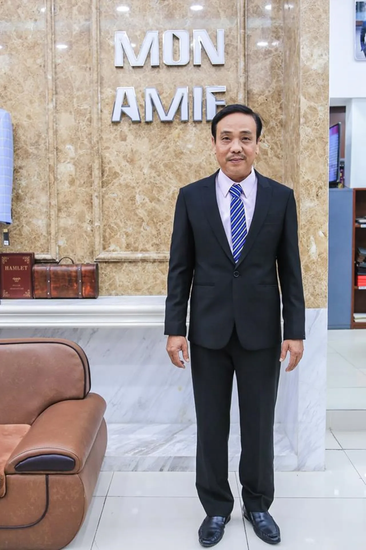 Black suit with a pale pink shirt and a blue striped tie, using a coloured shirt to make a black suit look younger