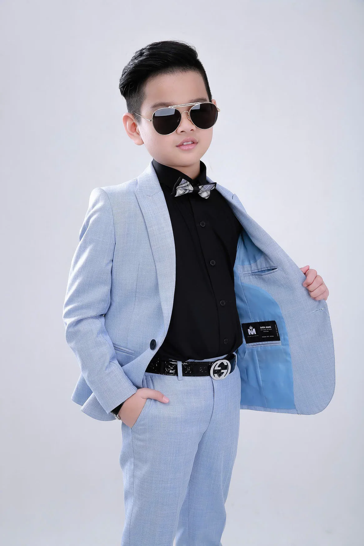 Boy opening the front of a pastel blue jacket to show the lining, black shirt