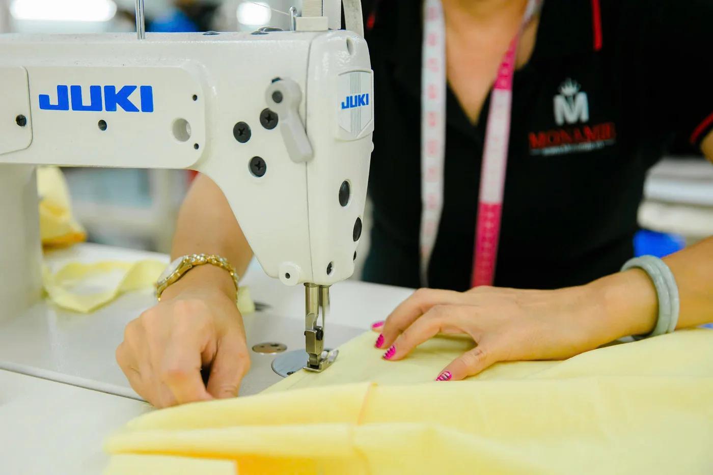 Nữ thợ may lót vàng nhạt trên máy Juki, công đoạn gắn lớp vải lót vào áo vest